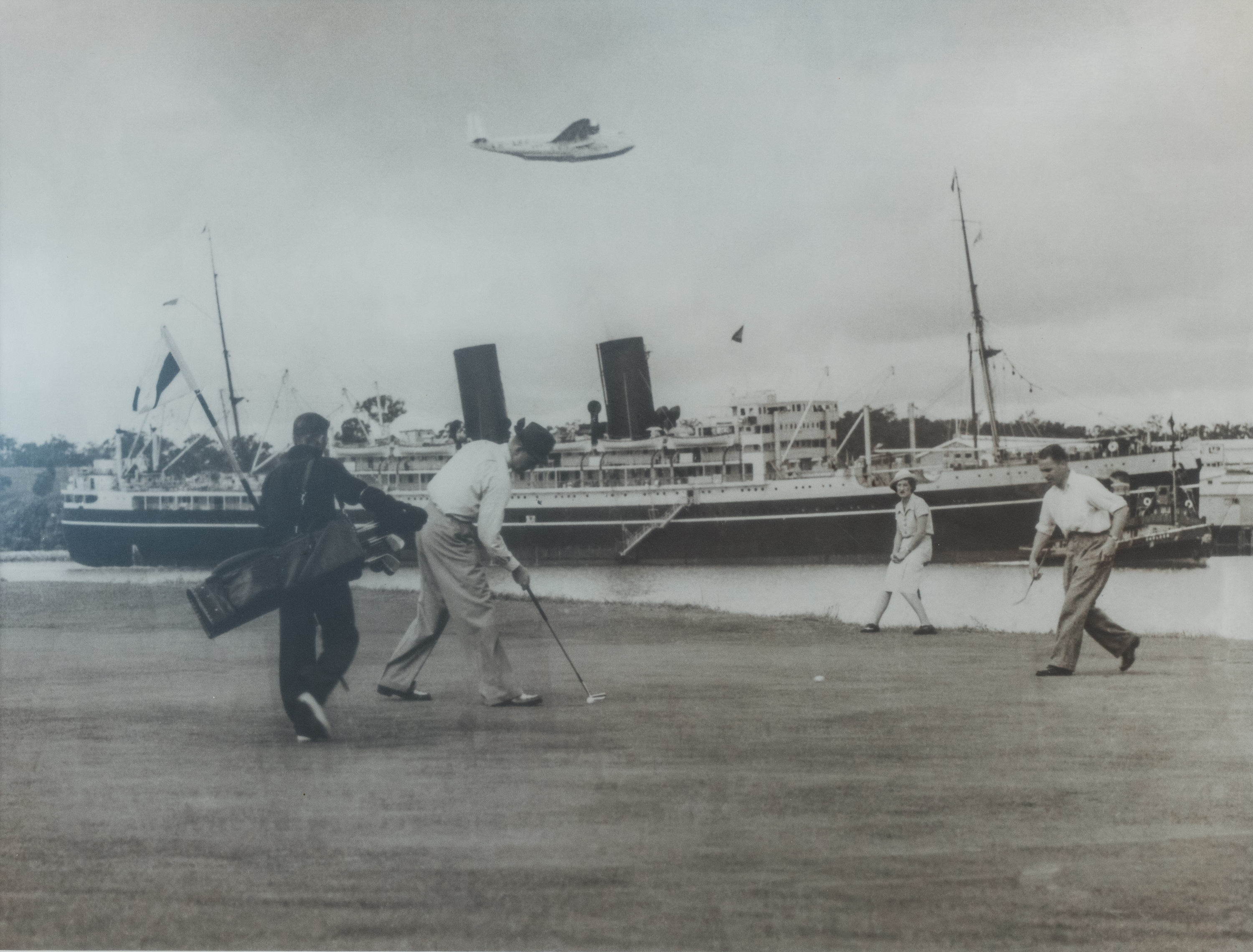 Golfers playing through with an Orient Line liner moored at Hamilton Cold Stores Wharf and a flying boat overhead, Royal Queensland Golf Club, c.1930s