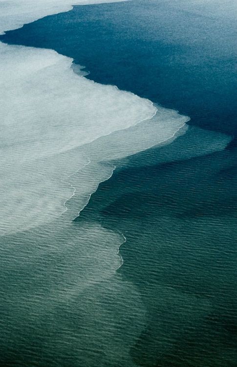 Aerial photograph of tidal water meeting at the bank, two distinct tones